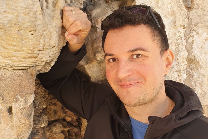 Dawid Surmik zdjęcie uśmiechniętego mężczyzny, który opiera się o skalną ścianę