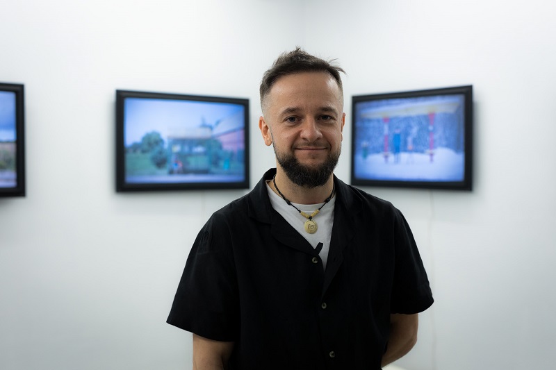 Dr Wojciech Kukuczka na tle swoich prac artystycznych z cyklu „Przystanki”, prezentowanych w galerii „Obserwacja” w Warszawie