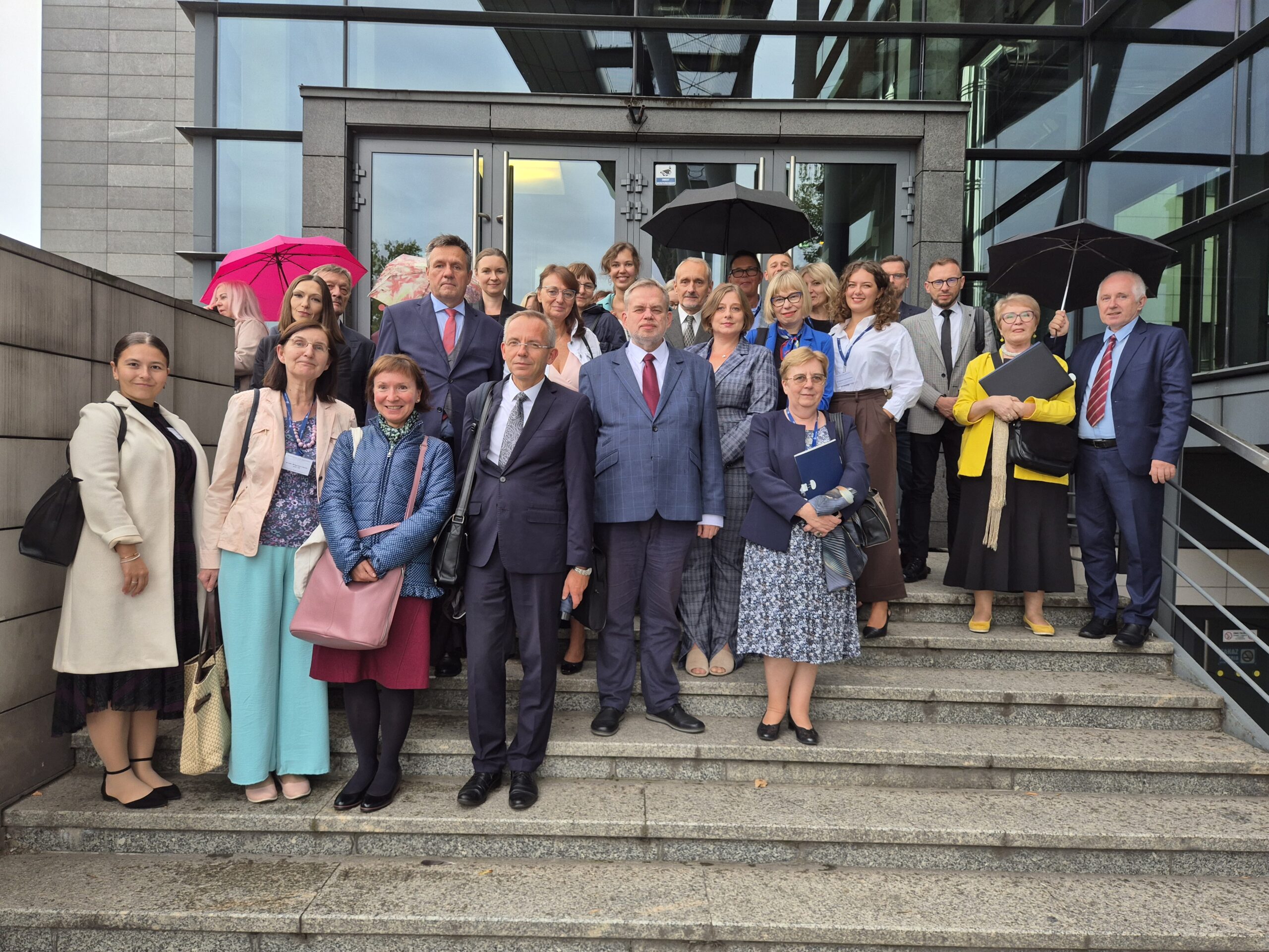 Zdjęcie przedstawiające uczestników konferencji stojących przed budynkiem 