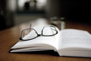 czarne okulary leżące na otwartej książce