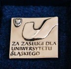 zdjęcie przedstawiające złotą odznakę "za zasługi dla Uniwersytetu Śląskiego"