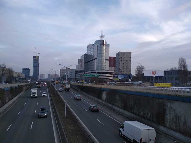 widok miasta, droga dwujezdniowa, przejeżdżające samochody a po bokach nowoczesne biurowce