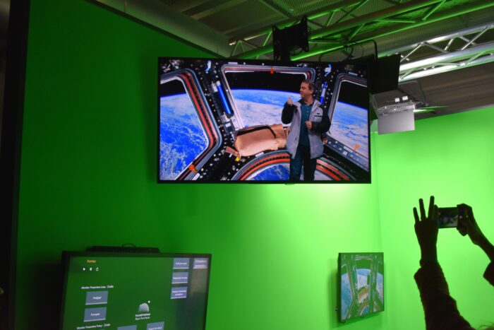 The screen on which one of the excursion participant seems to be standing in the spaceship. Ekran, na którym widać jednego z uczestników wycieczki stojącego na statku kosmicznym.