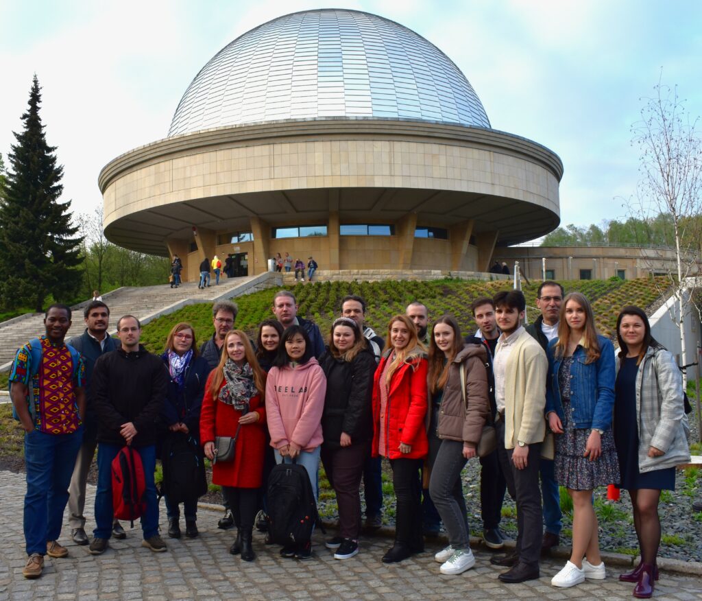 A group of people from different countries standing in front of the Planetarium. Grupa ludzi stojąca na tle Planetarium.