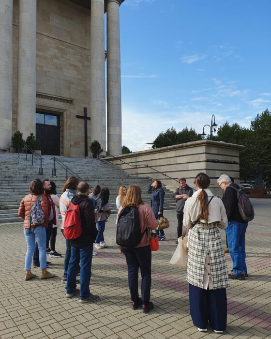 A group of people standing in front of the cathedral. Grupa ludzi stojąca przed katedrą.