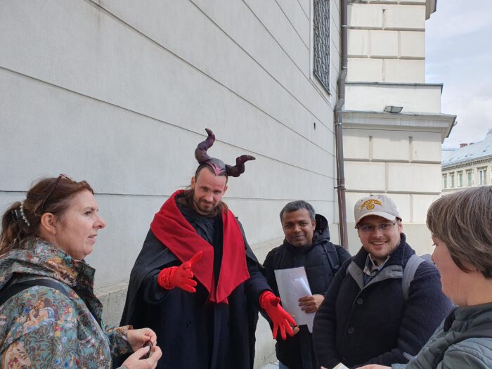 Internatilnal group of 4 people posing for a photo with a man dressed-up as a devil. Grupa 4 osób z różnych krajów pozująca do zdjęcia razem z mężczyzną przebranym za diobła.