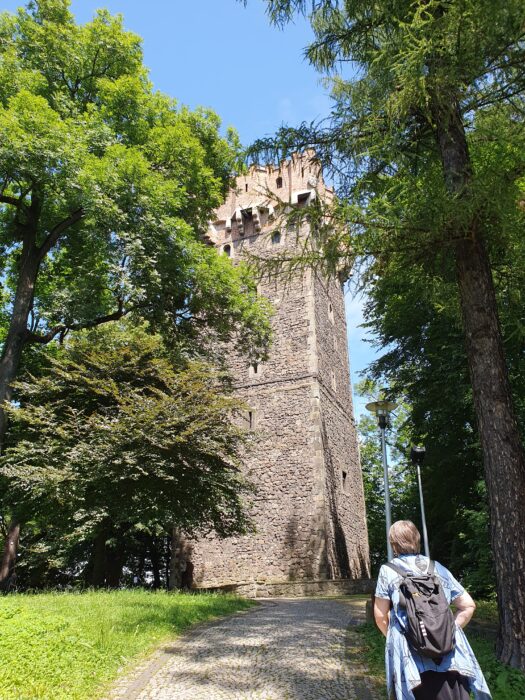 A woman going in the direction of the castle tower in the park. Kobieta idąca przez park w kierunku wieży.