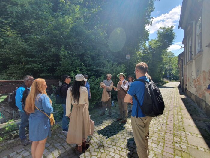 A group of people listening to the game guide. Grupa ludzi słuchająca instrukcji przewodnika gry.