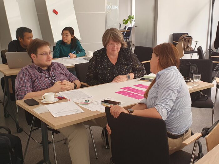 Four training participants during the training, talking to one of the trainers. Czworo uczestników podczas szkolenia, rozmawiającyh z jedną z trenerek.