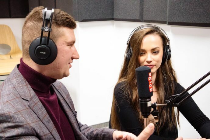 Dwoje osób siedzących przy radiowym mikrofonie.