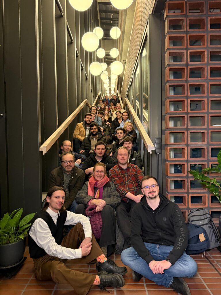 Grupa osób siedząca na schodach i pozująca do zdjęcia.