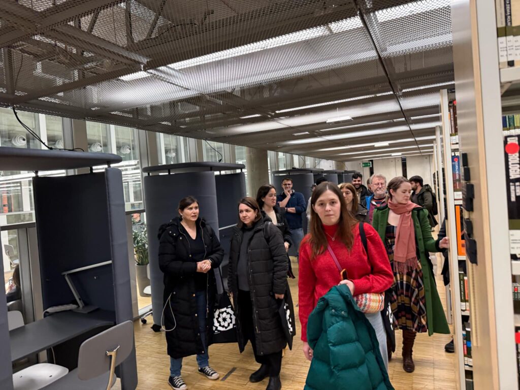 Grupa osób idąca przez bibliotekę.