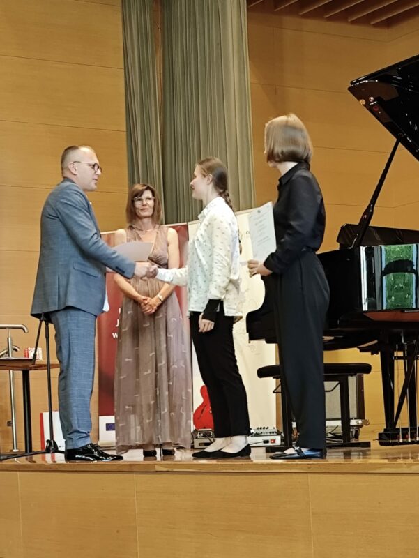 Yauheniya Kryval odbiera nagrodę z rąk dr. hab. Wojciecha Golca, w tle prof. dr hab. Ewa Grabowska-Lis - dyrektor artystyczny wydarzenia, fot. archiwum prywatne