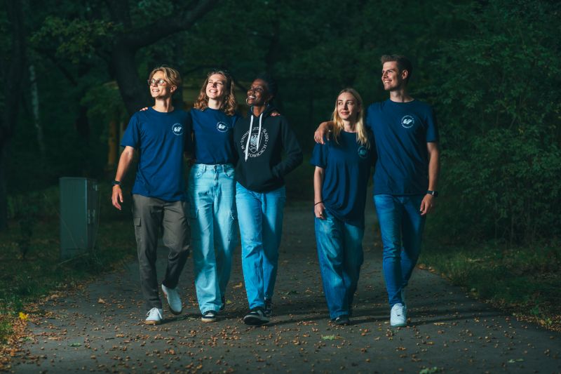 grupa studentów idzie razem. Wszyscy mają na sobie koszulki z logo uniwersytetu
