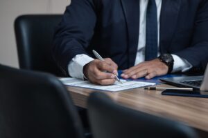 mężczyzna w garniturze podpisuje dokument