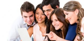 Zdjęcie przedstawia piątkę ludzi prawdopodobnie współpracowników, którzy przeglądają coś na laptopie