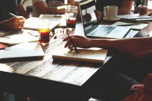 na zdjęciu widnieje stół, przy którym siedzą osoby notujące w zeszytach