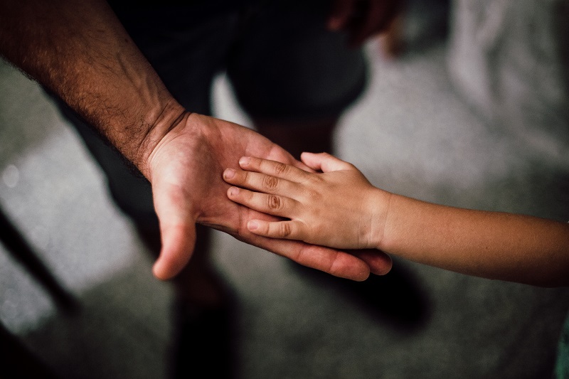 zbliżenie na dłoń osoby dorosłej trzymającej dłoń dziecka