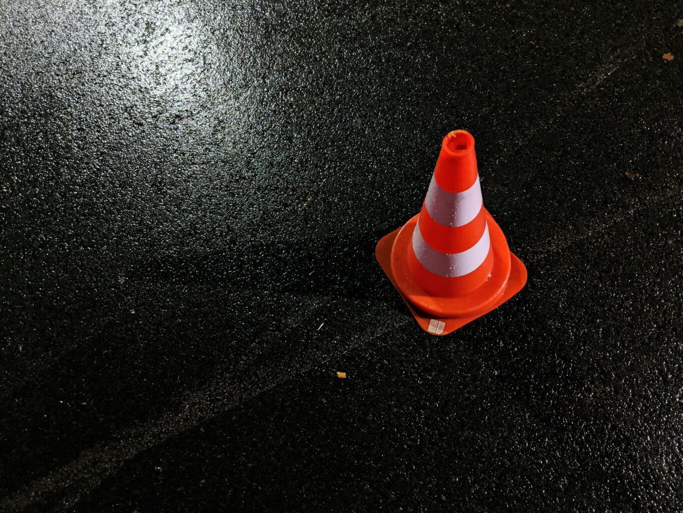 Zdjęcie przedstawia nawierzchnie drogi oraz pomarańczowy chopek drogowy