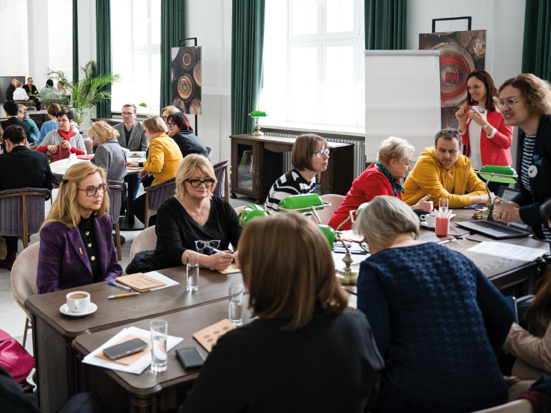 Obrazek wyrózniajacy - osoby siedzące przy biurkach. Spotkanie w ramach Klubu Nauczyciela
