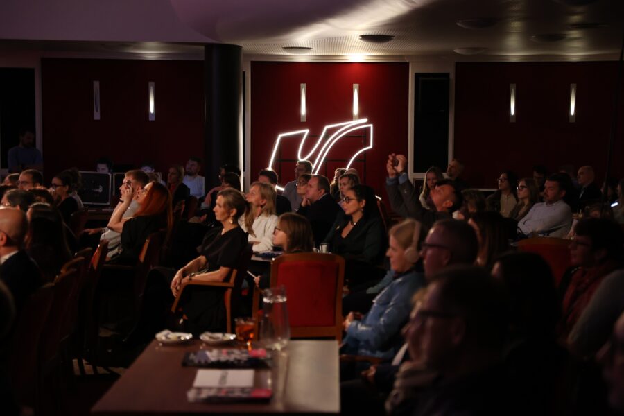 Sala pełna ludzi w tle neon z logotypem UŚ