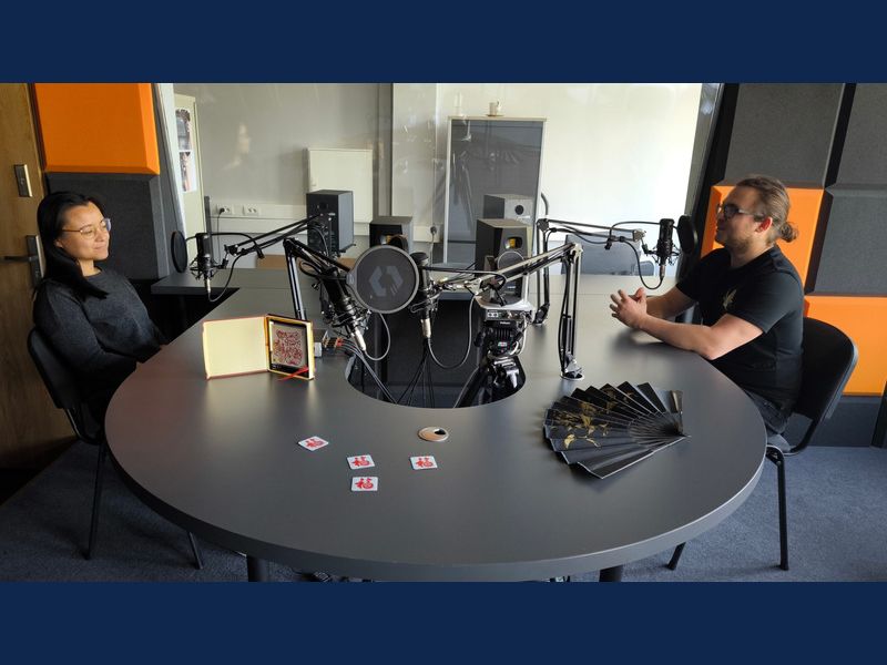Zdjęcie przedstawia prowadzącego i gościnię podcastu w studiu radiowym na WNS UŚ