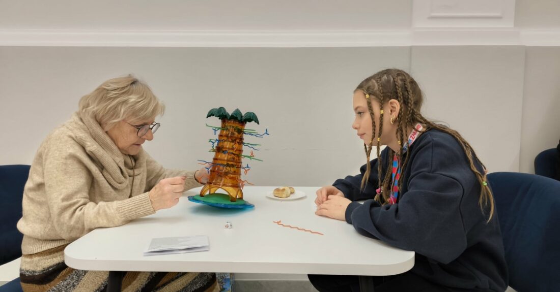 Zdjęcie przedstawia starszą kobietę i młodą dziewczynę grająca w grę spadające małpki