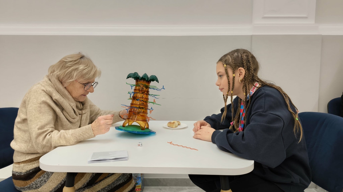 Zdjęcie przedstawia starszą kobietę i młodą dziewczynę grająca w grę spadające małpki