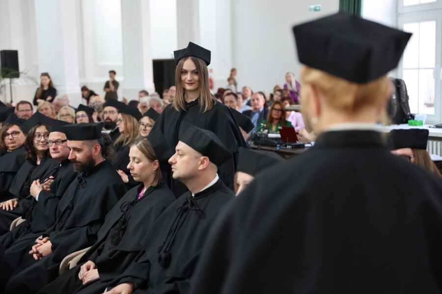 Przemówienie promotora w kierunku doktorantki w koło siedzą pozostali doktoranci