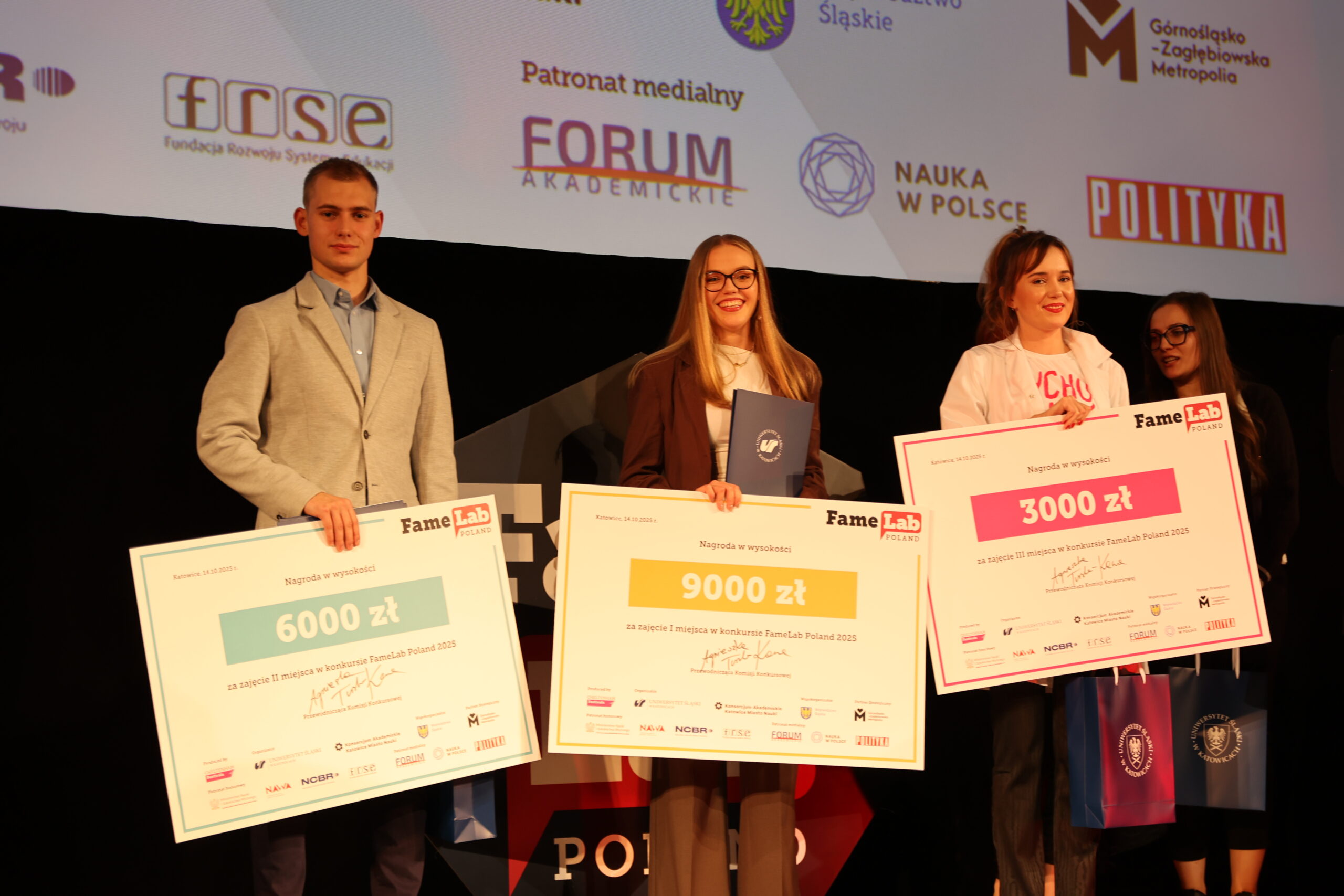 Na zdjęciu mężczyzna i dwie kobiety pozują do zdjęcia z bonami pieniężnymi