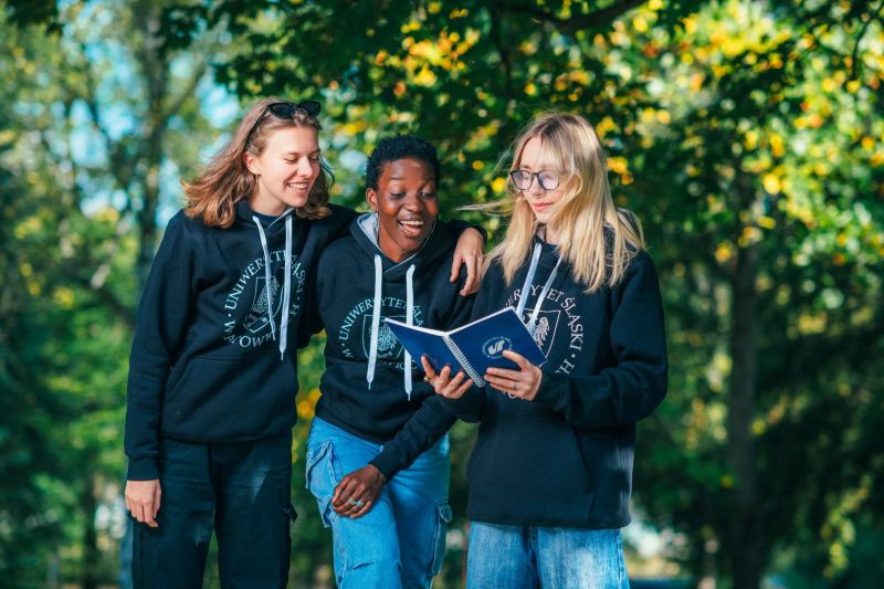 trzy studentki uśmiechniete czytające notatki
