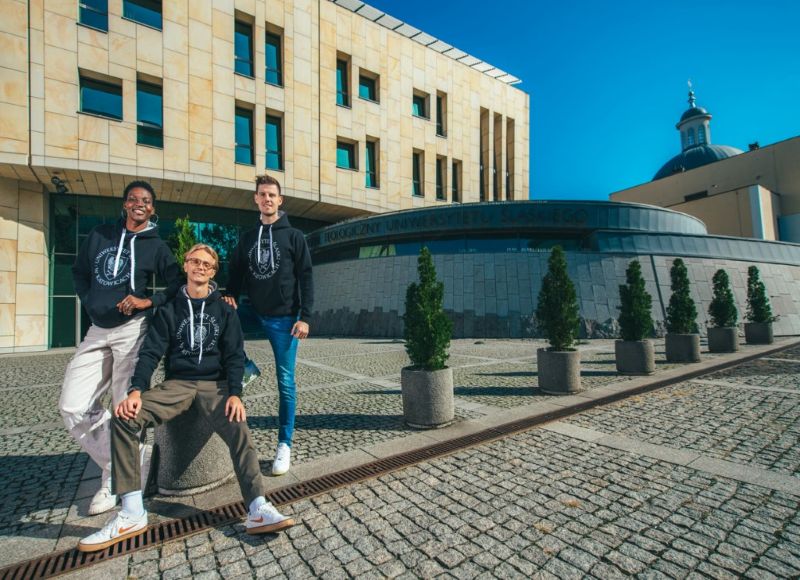 trójka studentów stoi przed budynkiem wydziału teologicznego