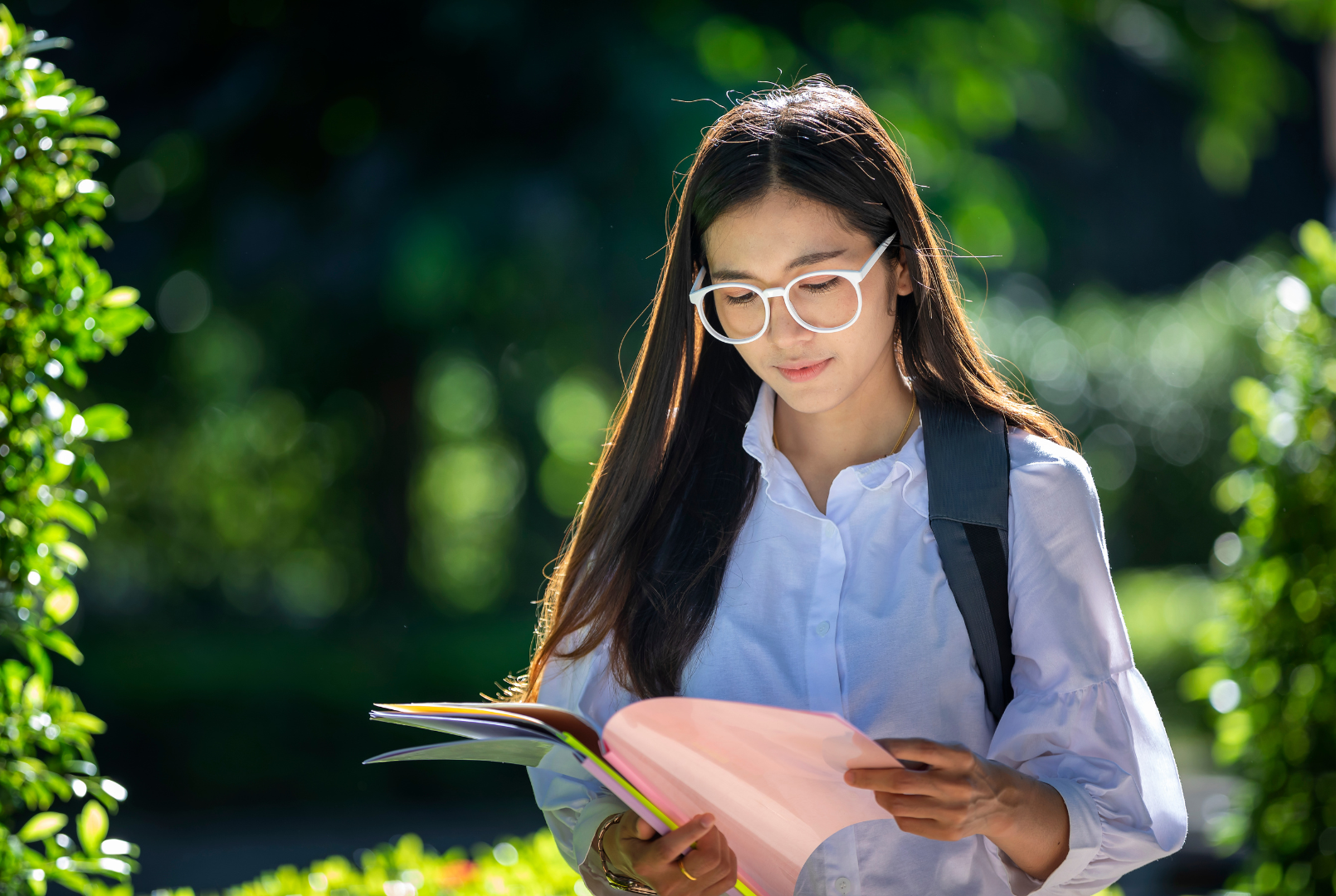 Studentka w okularach czyta książkę w tle park