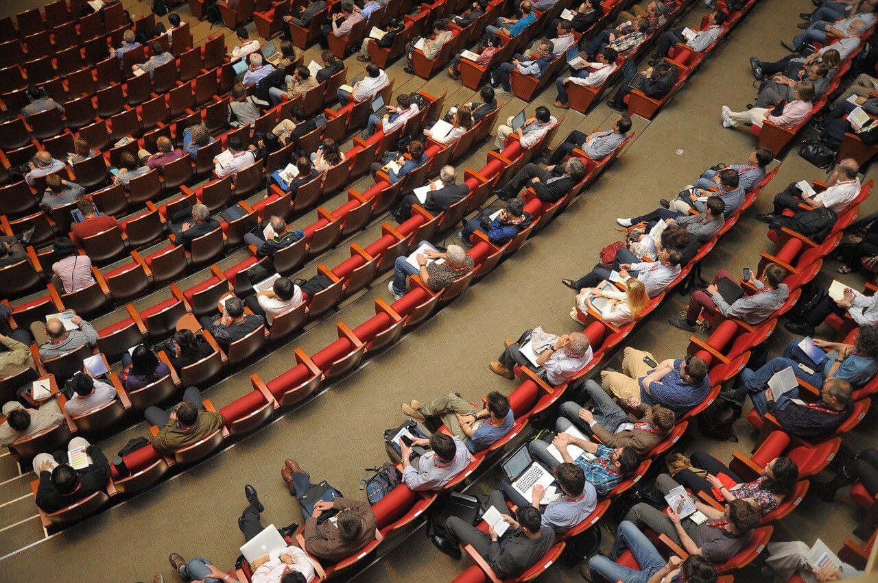 Ludzie siedzący na krzesłach na sali wykładowej