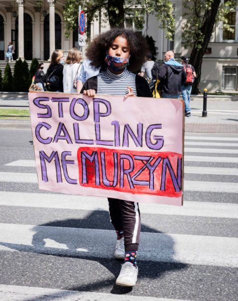 dziewczyna z transparentem Stop Calling Me Murzyn