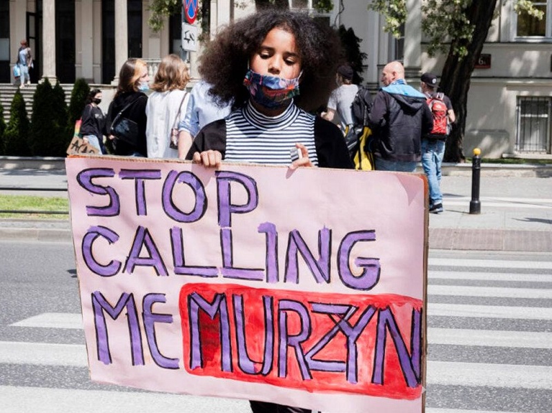 dziewczyna z transparentem Stop Calling Me Murzyn
