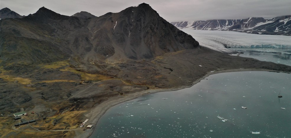 Zdjęcie z lotu ptaka – morze, lodowiec i w lewym dolnym rogu stacja polarna