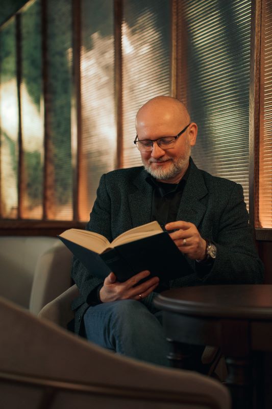 Dr Paweł Ćwikła czytający książkę