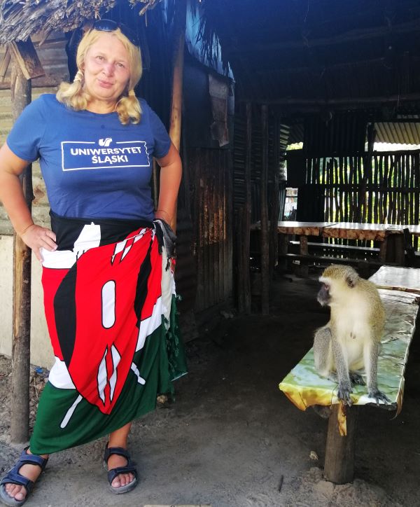 Dr Anna Watoła stoi obok domu, na ławce siedzi małpka