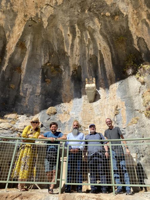 Grupa pięciu ludzi stojąca za barierką, za nimi wysoka skała