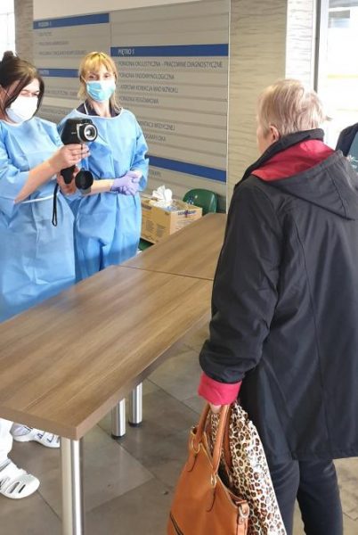 pracownicy medyczni mierząc pacjentom temperaturę za pomocą kamery termowizyjnej