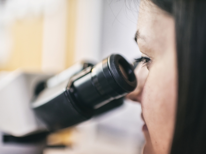 Zbliżenie na twarz kobiety, która patrzy przez okular mikroskopu / / Close-up of the face of a woman looking through the microscope