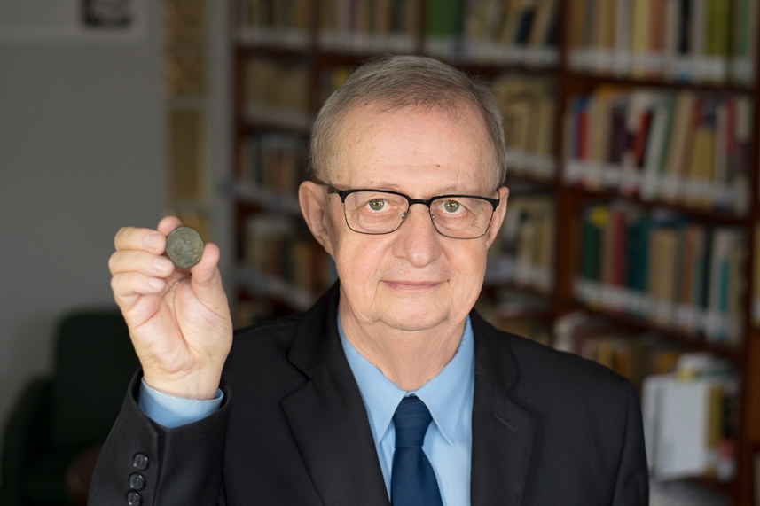 Prof. Wiesław Kaczanowicz prezentuje jedną z rzymskich starożytnych monet