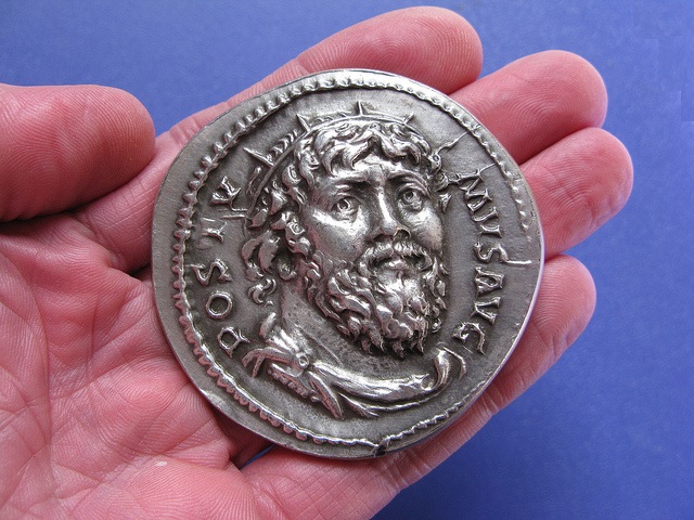 Przykładowy medalion prezentowany na dłoni z wizerunkiem jednego z cesarzy