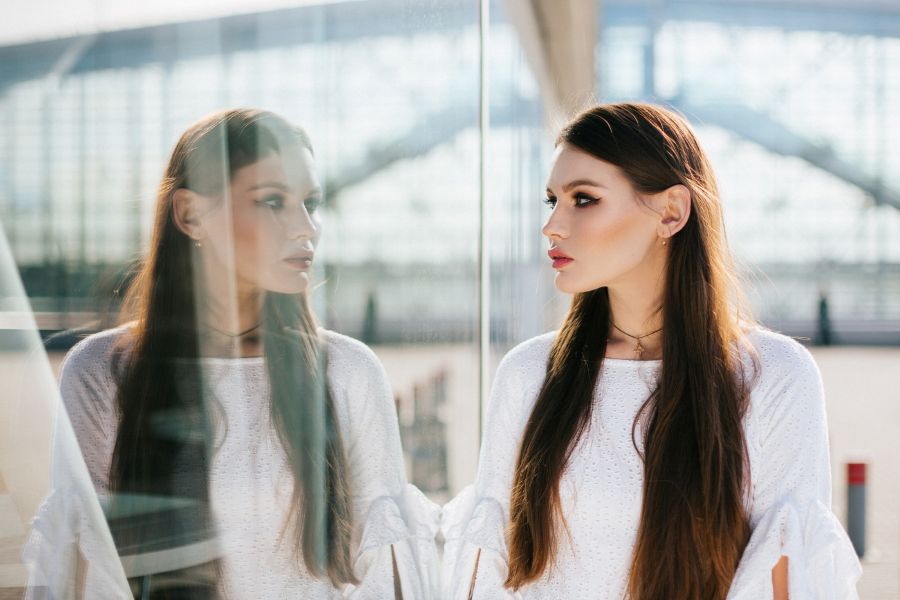 Kobieta, patrzy na swoje odbicie w szybie