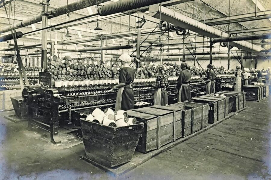 Historyczne zdjęcie włókniarek pracujących w fabryce przy taśmie produkcyjnej / An old photo of textile workers in a factory by the assembly line