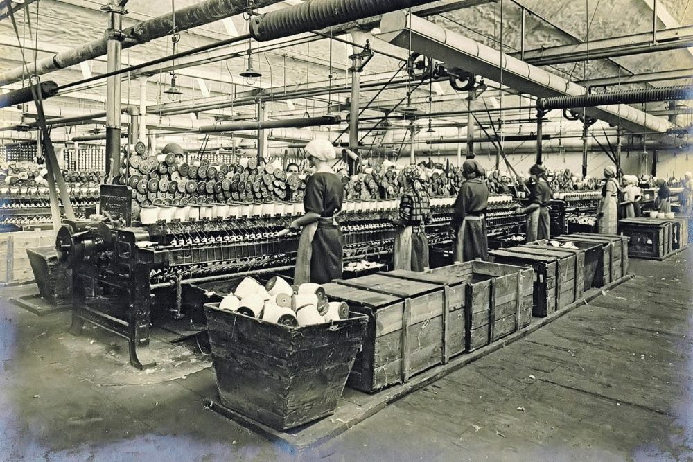 Historyczne zdjęcie włókniarek pracujących w fabryce przy taśmie produkcyjnej