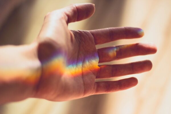 otwarta dłoń, na której odbijają się załamanie światła imitujące kolory tęczy, domena: pixabay.com