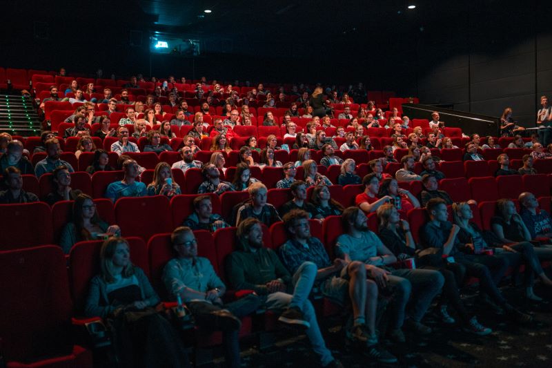 Pełna sala kinowa z ludźmi wpatrującymi w ekran
