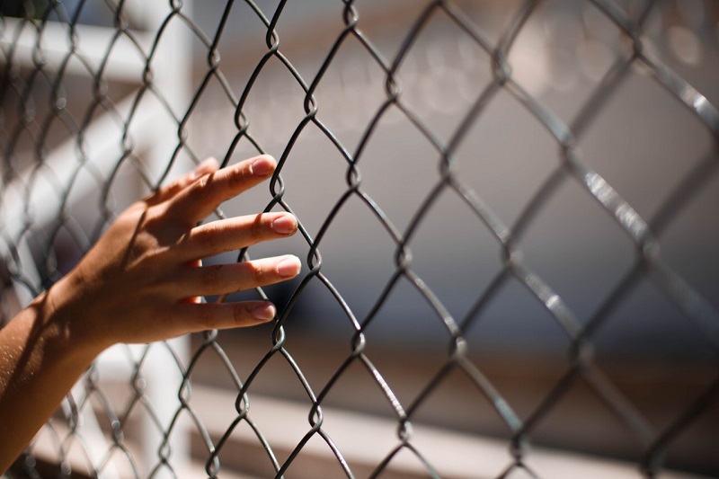 zdjęcie dłoni trzymającej kratę więzienną